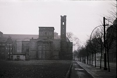 Black-and-white shot of a historic European church with Romanesque architecture—prominent round arches, a tall bell tower, an...