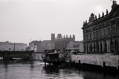Black-and-white urban riverside scene featuring a grand neoclassical building wi...
