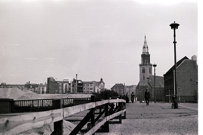 Black-and-white urban street scene featuring a prominent church steeple with a c...