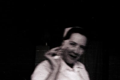 Vintage black-and-white close-up of a person adjusting a tie, likely in a formal setting. Soft focus and grainy texture sugge...
