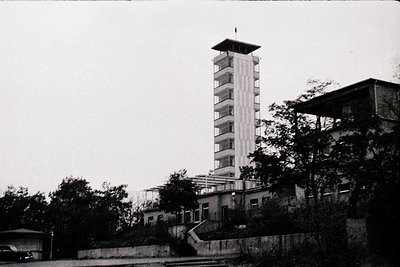 Mid-century Brutalist tower block with flat balconies, flanked by low-rise concrete structures. Architectural Brutalism
