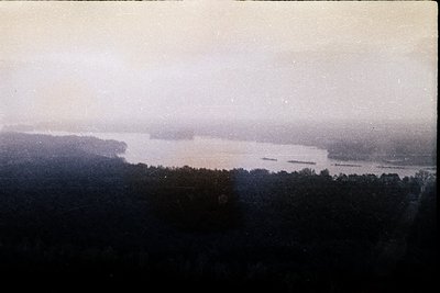 Vintage sepia-toned aerial view of a wide river winding through forested lowlands, likely early 20th century. Dense tree cove...