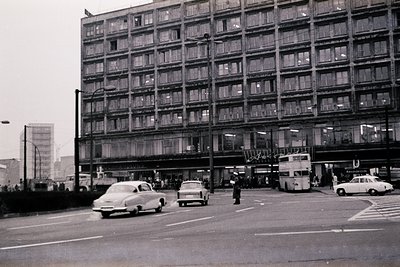 Mid-century Brutalist apartment block with exposed concrete facade and uniform rectangular windows. Classic 1960s urban desig...