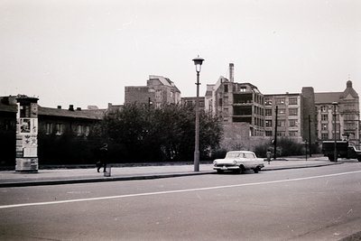 Mid-century urban street scene featuring Soviet-era architecture. Multi-story brick buildings with flat roofs and minimalist ...