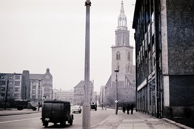 Black-and-white urban street scene featuring a prominent **brick church with a tall steeple** and **baroque architectural det...