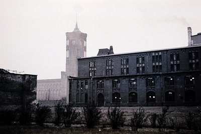 Industrial-era brick building with arched windows and arched doorways, likely a factory or warehouse. Prominent clock tower w...