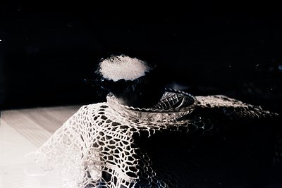 Vintage lace collar with intricate geometric patterns, backlit for dramatic contrast. Likely 1950s–1970s European or North Am...