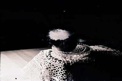 Vintage lace scarf draped over a dark surface, showcasing intricate floral patterns and delicate embroidery. The sepia-toned ...