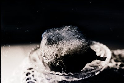Close-up of a vintage camera lens with visible wear, showcasing soft focus and film grain. The lens cap is partially removed,...