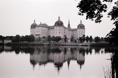 Symmetrical Baroque-style castle reflected in calm waters, surrounded by dense greenery. Likely #Österreich’s önbrunn or simi...