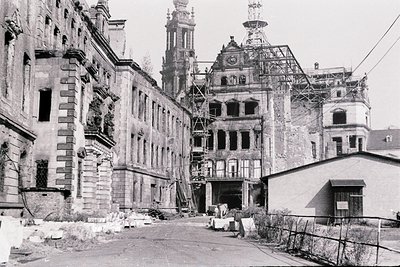 Black-and-white shot of a mid-20th-century European courtyard in ruins, showcasing historic architecture with ornate facades ...