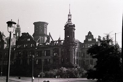 Vintage black-and-white shot of a grand, multi-towered building in partial ruin, featuring Gothic Revival architecture with o...