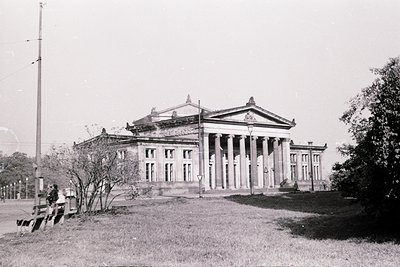 Neoclassical building with prominent columns and triangular pediment, likely institutional or governmental. Symmetrical facad...