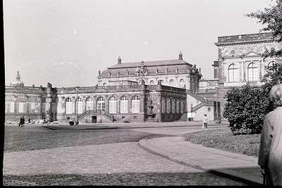 Neoclassical palace with arched colonnades and sculptural details, likely early 20th century. Symmetrical design features gra...