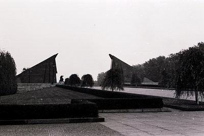 Monumental concrete pyramids flank a wide, paved plaza with geometric landscaping. Minimalist Soviet-era architecture, likely...