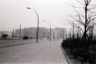 Vintage black-and-white street scene featuring Soviet-era concrete apartment blocks in the background, likely Eastern Europe....