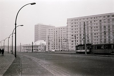 Soviet-era urban landscape featuring Brutalist high-rise apartment blocks with uniform concrete facades and repetitive window...