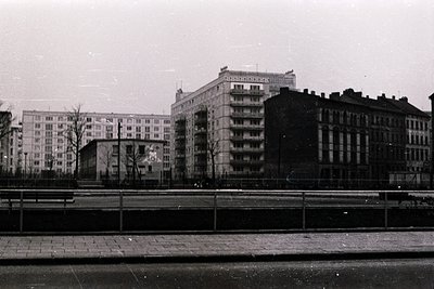 Mid-century Soviet-era apartment blocks with brutalist concrete facades, featuring balconies and large windows. Foreground sh...