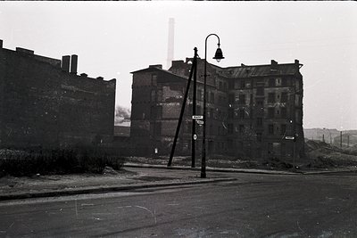 Mid-20th century urban decay: multi-story brick buildings with exposed wiring, peeling paint, and boarded windows. A vintage ...