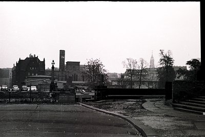 Mid-20th century urban scene featuring a bridge with vintage vehicles, likely . Prominent brick buildings with classic Europe...