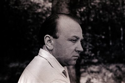 Portrait of a man in mid-profile, wearing a light-colored, high-collar shirt. His short hair and clean-shaven face suggest a ...