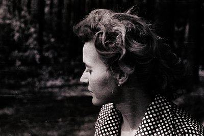 Black-and-white portrait of a woman with voluminous 1960s-style updo, wearing a polka-dot blouse. Soft focus and natural ligh...