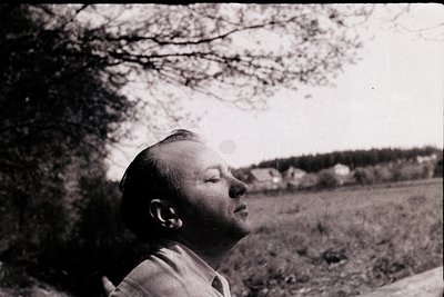 Black-and-white portrait of a man gazing upward, likely mid-20th century. His short hair and light jacket suggest a casual, o...