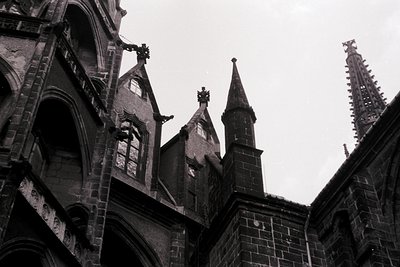 Gothic stone spires and buttresses dominate this black-and-white architectural detail, showcasing intricate tracery and point...