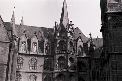 Gothic-style brick building with steeply pitched roofs, ornate stone tracery, and pointed arches—likely a European cathedral ...