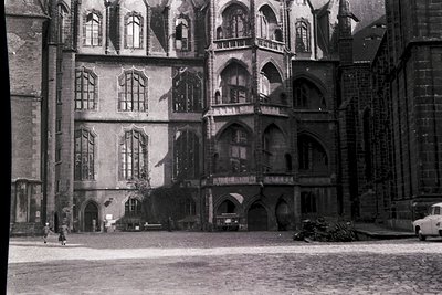 Gothic-style courtyard façade with pointed arches, tracery windows, and decorative stonework. Cobblestone courtyard with mini...