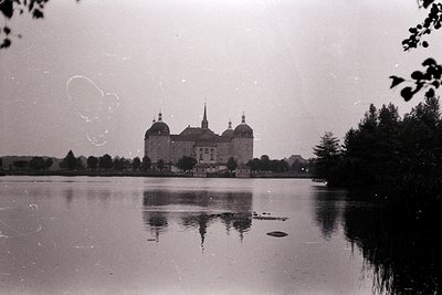 Vintage black-and-white shot of **Marienborg Palace** in Denmark, reflecting on a serene lake. Baroque architecture with dome...