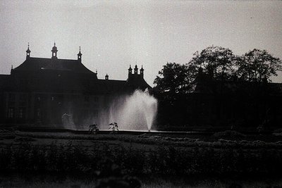 Mid-20th century estate with grand Tudor-style mansion featuring steep gables, dormer windows, and decorative spires. Central...