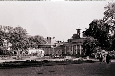 Neoclassical villa with symmetrical colonnade, set in landscaped gardens. Central clock tower and mansard roof detail. Early ...