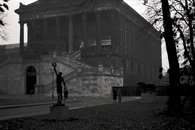 Neoclassical building with grand staircase and balustrade, likely a cultural institution. Black-and-white photo captures thre...