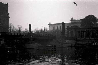 Black-and-white shot of a grand neoclassical bridge spanning a calm waterway, flanked by ornate stone balustrades. Prominent ...
