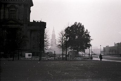 Black-and-white urban scene featuring a grand neoclassical building with columns and arched windows, likely a government or i...