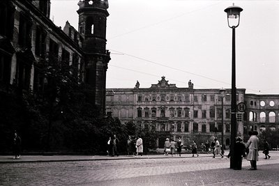 Black-and-white street scene featuring grand neoclassical architecture with ornate facades, arched windows, and decorative st...