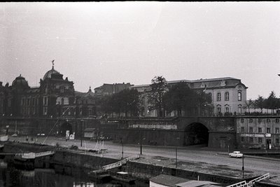 Historic urban scene featuring a grand, ornate building with domed towers and classical architecture, likely a railway statio...
