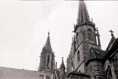 Gothic spires and intricate stonework of a cathedral façade, likely European. Symmetrical twin towers with ornate pinnacles a...