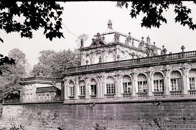 Baroque-style palace with intricate stone carvings, arched windows, and statues adorning the rooftop. Symmetrical facade fram...