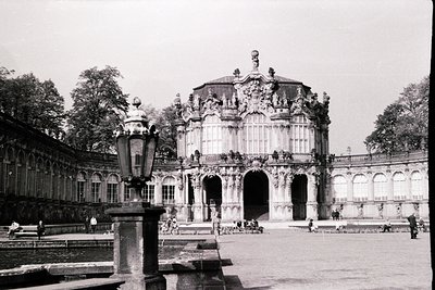 Baroque-style palace façade with ornate sculptures, arched gateways, and decorative balustrades. Central dome flanked by symm...