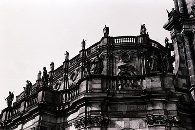 Baroque-style stone façade featuring ornate balustrades, statues, and intricate carvings. Likely European opera house or thea...