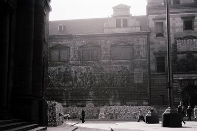 Black-and-white courtyard featuring ornate Baroque-style façade with intricate relief sculptures depicting classical figures ...