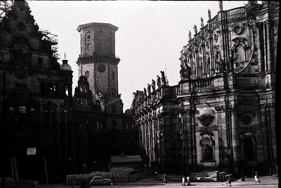 Baroque-style cathedral façade with intricate stone carvings, flanked by a tall bell tower under renovation. Mid-20th century...