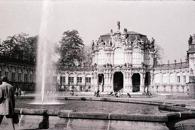 Baroque-style palace façade with cascading fountain in foreground. Ornate columns, arched windows, and sculptural details dom...