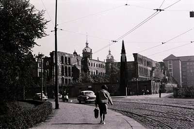 Mid-century European street scene with vintage tram tracks and overhead wires. Prominent historic architecture featuring orna...