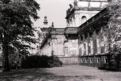 Neoclassical façade featuring tall columns, ornate balustrades, and sculptural details. Symmetrical design with arched window...