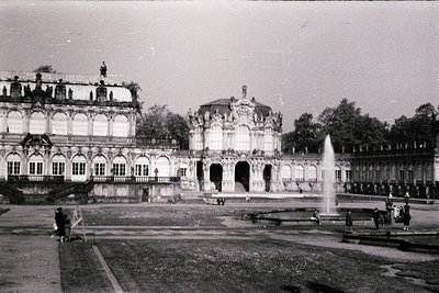 Baroque-style palace courtyard with ornate façade, central fountain, and symmetrical gardens. Likely **18th-century** Europea...