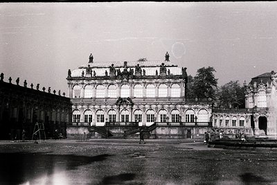 Baroque-style palace façade with ornate balconies, statues, and arched windows, likely 18th-century European. Symmetrical des...