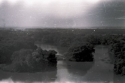 Vintage aerial view of a flooded, forested landscape with scattered tree clusters and waterlogged terrain. Likely early-to-mi...